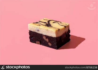 Slice of cheesecake brownie in bright light on a pink-colored table. Delicious homemade brownie with a layer of cream cheese, minimalist on a pink background
