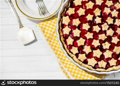 slice of delicious homemade sour cherry pie on plate. Bowl with whipped cream, dessert forks and whole tart on wooden table, classic recipe, view from above. slice of delicious homemade sour cherry pie on plate.