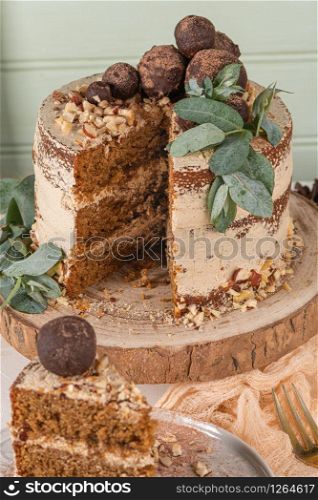 Slice of delicious naked chocolate and hazelnuts cake on table rustic wood kitchen countertop.