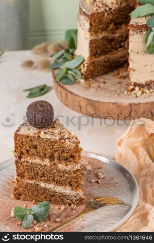 Slice of delicious naked chocolate and hazelnuts cake on table rustic wood kitchen countertop.