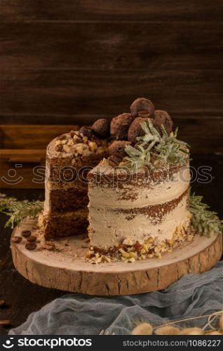 Slice of delicious naked coffee and hazelnuts cake on table rustic wood kitchen countertop.