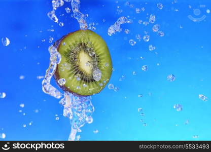 slice of kiwi in the water with bubbles, on blue background