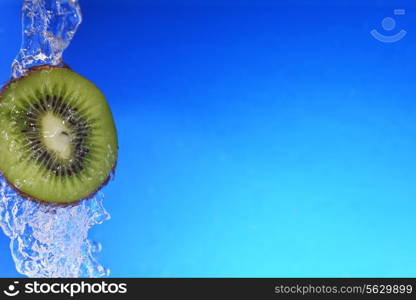 slice of kiwi in the water with bubbles, on blue background