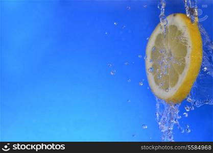 slice of lemon in the water with bubbles, on blue background