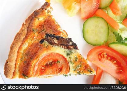 Slice of mushroom quiche on a plate with a salad