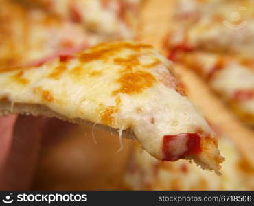 Slice of pizza, held up by a person
