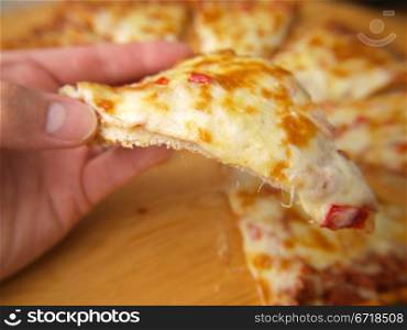 Slice of pizza, held up by a person
