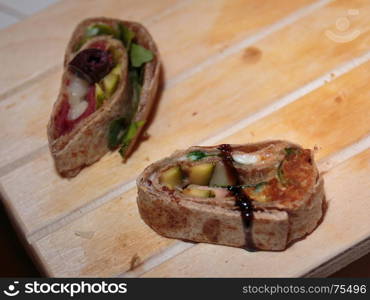 Slice of Snack Rolled and Filled with Fresh Vegetables and Salmon on Wooden Board