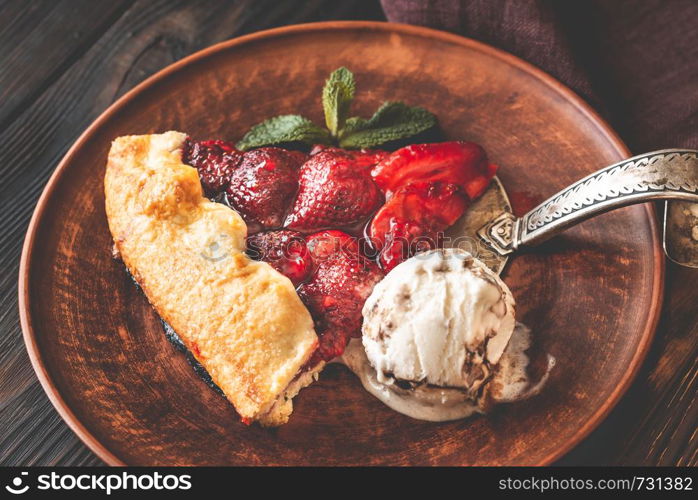 Slice of strawberry galette served with ice-cream on the brown plate