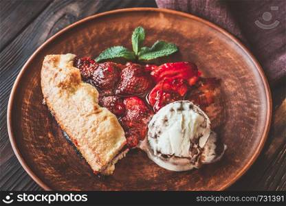 Slice of strawberry galette served with ice-cream on the brown plate