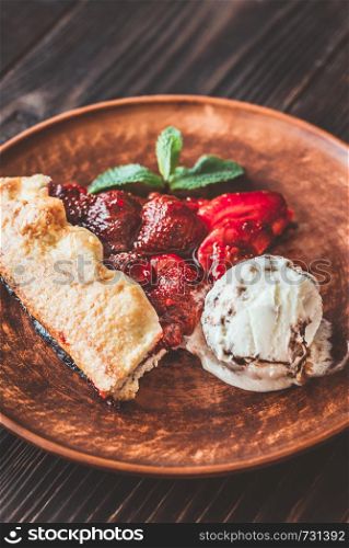 Slice of strawberry galette served with ice-cream on the brown plate