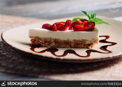 Slice of strawberry yogurt or coconut cake decorated with fresh fruits and mint on a plate. Delicious and sweet pink cake for Valentines or birthday party. Homemade bakery concept. Selective focus