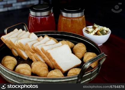 slice toast bread and croissant in tray with jam and butter