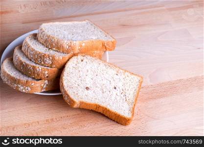 Slice whole wheat bread on wooden floor background.