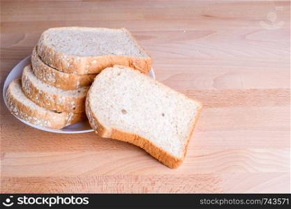 Slice whole wheat bread on wooden floor background.