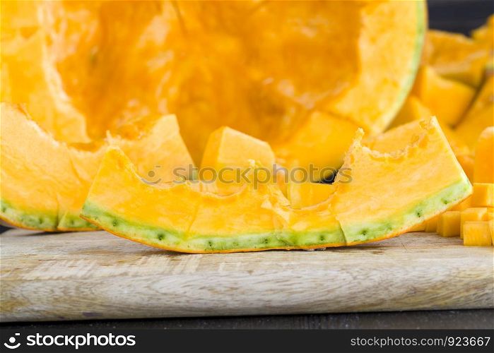 sliced and diced orange pumpkin on the kitchen table, close-up of raw vegetables before cooking. sliced and diced orange pumpkin