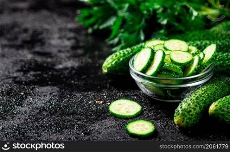 Sliced and whole cucumbers on the table. Against a dark background. High quality photo. Sliced and whole cucumbers on the table.