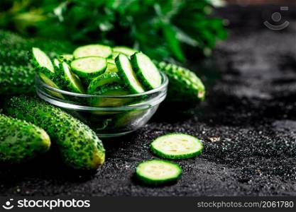 Sliced and whole cucumbers on the table. Against a dark background. High quality photo. Sliced and whole cucumbers on the table.