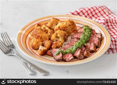 Sliced beef steak garnished with baked cauliflower florets