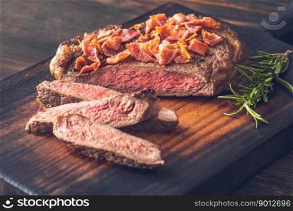 Sliced beef steak with crumbled bacon garnished with rosemary