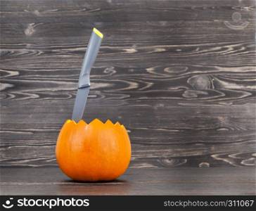 Sliced black pumpkin on a black wooden surface, kitchen. Pumpkin cut knife