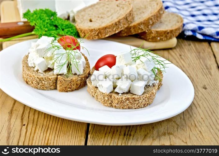 Sliced bread with cheese, tomato and dill on a plate, napkin, parsley, knife on background wooden boards
