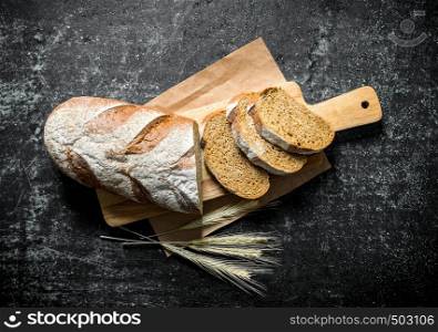 Sliced bread with spikelets. On dark rustic background. Sliced bread with spikelets.