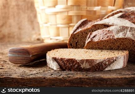 Sliced brown bread with knife on wooden table