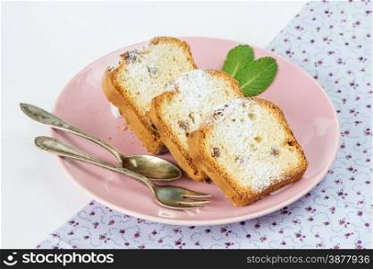 Sliced cake with raisins on a pink porcelain plate, isolated on a white background