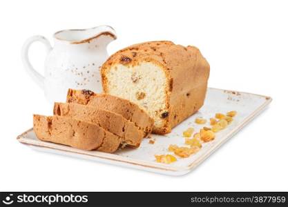 Sliced cake with raisins on a porcelain plate and vintage milk jug, isolated on a white background