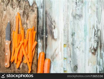Sliced carrots on a cutting Board with a knife. On wooden background. Sliced carrots on a cutting Board with a knife.