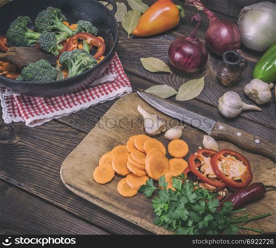 sliced carrots on a wooden kitchen board and fresh vegetables, top view, vintage toning