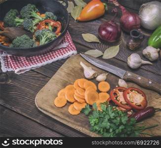 sliced carrots on a wooden kitchen board and fresh vegetables, top view, vintage toning
