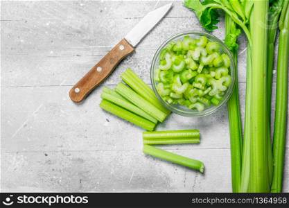 Sliced celery in a bowl with a knife. On rustic background. Sliced celery in a bowl with a knife.