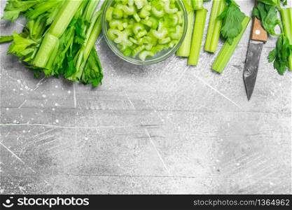 Sliced celery in a bowl with a knife. On rustic background. Sliced celery in a bowl with a knife.