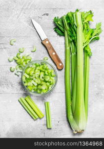 Sliced celery in a bowl with a knife. On rustic background. Sliced celery in a bowl with a knife.