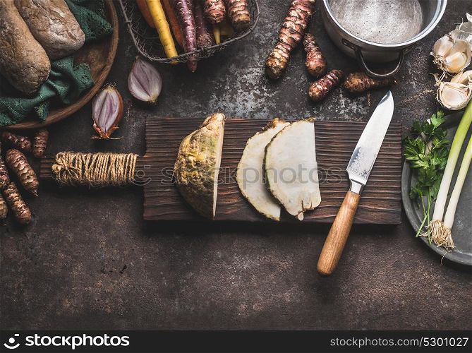 Sliced celery on wooden cutting board with knife on rustic kitchen table background with pot and others root vegetables ingredients for tasty cooking, top view. Healthy and clean food