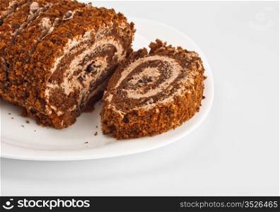 sliced chocolate roll on white dish, grey background