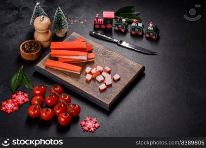 Sliced crab sticks on a cutting Board with a knife. On black rustic background. Crab sticks on a cutting Board with a knife. On a black christmas table
