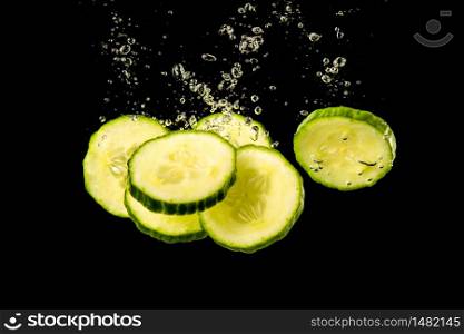 Sliced cucumber splashing water isolated on black background. Health and cosmetics concept. Underwater. Sliced cucumber splashing water isolated on black background. Health and cosmetics concept.