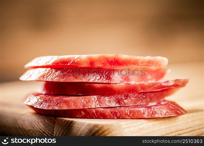 Sliced delicious salami sausage on the table. On a wooden background. High quality photo. Sliced delicious salami sausage on the table.