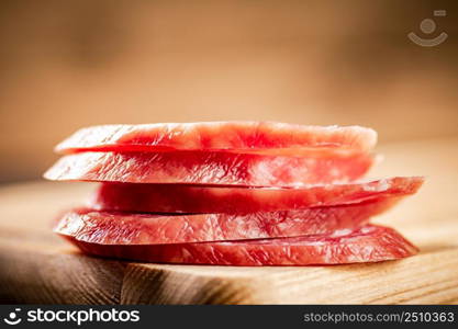 Sliced delicious salami sausage on the table. On a wooden background. High quality photo. Sliced delicious salami sausage on the table.