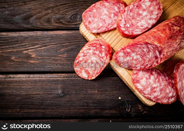 Sliced delicious salami sausage on the table. On a wooden background. High quality photo. Sliced delicious salami sausage on the table.