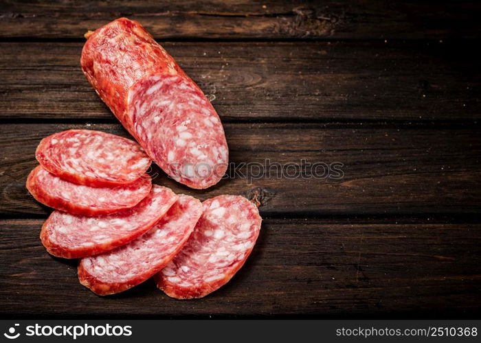 Sliced delicious salami sausage on the table. On a wooden background. High quality photo. Sliced delicious salami sausage on the table.