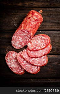 Sliced delicious salami sausage on the table. On a wooden background. High quality photo. Sliced delicious salami sausage on the table.