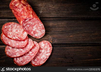 Sliced delicious salami sausage on the table. On a wooden background. High quality photo. Sliced delicious salami sausage on the table.