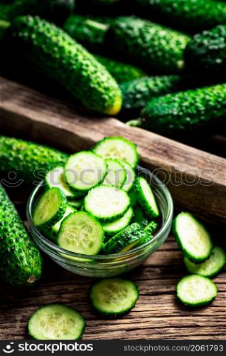 Sliced fresh cucumbers in a glass bowl. On a wooden background. High quality photo. Sliced fresh cucumbers in a glass bowl.