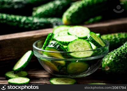 Sliced fresh cucumbers in a glass bowl. On a wooden background. High quality photo. Sliced fresh cucumbers in a glass bowl.