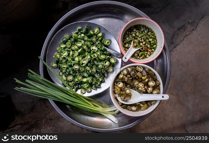 Sliced fresh green chili spur pepper, Pickled chillies in vinegar, Chilli fish sauce and Spring onions on Stainless steel tray. Side dishes for more tasty, Top view, Free space for text. Select focus.