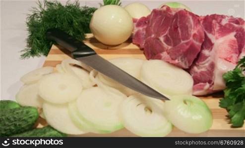 Sliced fresh pork meat and vegetables on wooden cutting board close-up dolly shot